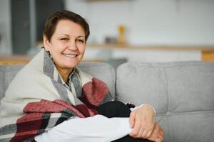 portrait of senior woman at home on sofa with plaid photo