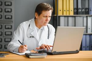 Mid age female doctor writing prescription photo