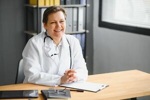 Portrait of middle age female doctor is wearing a white doctor's coat with a stethoscope around her neck. photo