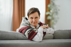 portrait of senior woman at home on sofa with plaid photo