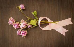 Disparo de el seco rosas envuelto en el rosado cinta, símbolo de el pecho cáncer conciencia. concepto foto