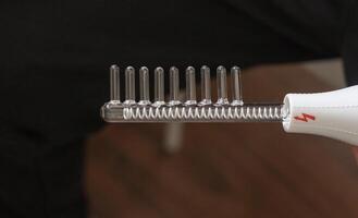 Close up shot of the high frequency comb tool for hair and scalp treatment. Healthcare photo