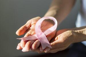 Shot of a woman holding pink ribbon, symbol of a breast cancer awareness. Concept photo