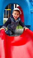 Little Boy Enjoying a Colorful Slide. A little boy playing on a red and blue slide. A little boy playing on a red and blue slide photo