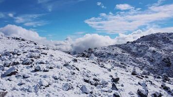 Low flight of a drone over rocks and a volcanic slope covered with snow video