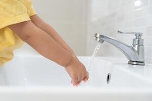 little kid hands wash with soap bubbles and rinse with clean water to prevent and stop the spread of germs after back to home, virus or covid19. Good health and good personal hygiene, virus, bacteria photo