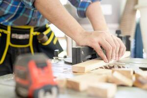 hombre propietario un pequeño mueble negocio es preparando madera para producción. carpintero masculino es ajustar madera a el deseado tamaño. arquitecto, diseñador, incorporado, profesional madera, artesano, taller. foto