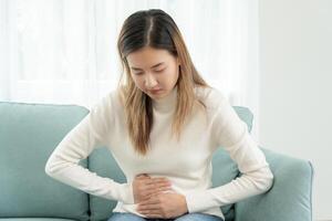 stomach ache. Asian women have abdominal pain, indigestion, gastritis, menstrual cramps, flatulence, diarrhea, distention, colon cancer, belly inflammation problem, suffer food poisoning, abdomen photo