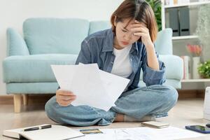 Stressed and headache asian woman with large bills or invoices no money to pay to expenses and credit card debt. shortage, Financial problems, mortgage, loan, bankruptcy, bankrupt, poor, empty wallet photo