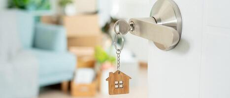 Moving house, relocation. The key was inserted into the door of the new house, inside the room was a cardboard box containing personal belongings and furniture. move in the apartment, banner photo