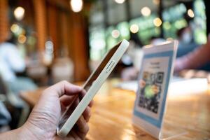 Woman use smartphone to scan QR code for order menu in cafe restaurant with a digital delivery. Choose menu and order accumulate discount. E wallet, technology, pay online, credit card, bank app. photo