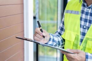 el inspector o ingeniero está inspeccionando la construcción y el aseguramiento de la calidad de la nueva casa usando una lista de verificación. ingenieros o arquitectos o contratistas trabajan para construir la casa antes de entregársela al propietario foto