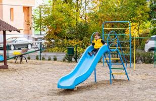 A Joyful Little Boy Sliding Down a Vibrant Blue Slide. A little boy playing on a blue slide photo