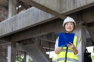 Asian woman engineer in full safety gear is inspecting inside the building structure for investigation over specification on construction site industry and quality control usage photo