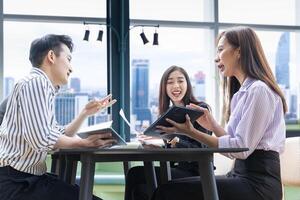 equipo de joven asiático empresario tener pequeño equipo reunión para próximo proyecto para márketing y rebaja administración con rascacielos ver para negocio puesta en marcha y educación uso foto