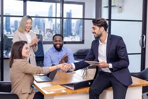 caucásico negocio equipo líder felicitar su compañero de equipo empleado para el excepcional logro equipo actuación por sacudida mano en moderno oficina lugar de trabajo con rascacielos ver foto