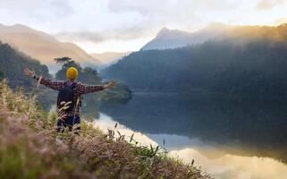 Asian naturalist hiking at destination while exploring wildlife in the forest by the lake for surveying and discovering the rare biological diversity and ecologist on field study in autumn photo