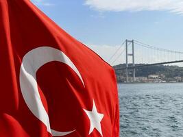 turco bandera revoloteando en el viento con Estanbul y el dorado cuerno puente en el fondo, Turquía foto