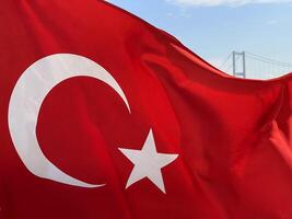 Turkish flag fluttering in the wind with Istanbul and the Golden Horn Bridge in the background, Turkey photo