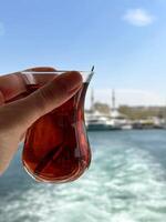 A cup of tea in a woman's hand against the background of the Bosphorus and Istanbul photo