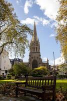 pacífico ver de un histórico Iglesia aguja en Londres desde un parque banco - un urbano oasis en medio de otoñal belleza foto