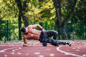 un sin camisa hombre ejecutando un impresionante truco en un corriendo pista. un sin camisa hombre es haciendo un truco en un corriendo pista foto