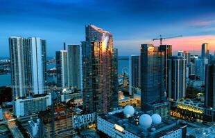 aéreo ver de Miami ciudad a noche desde edificio cima. capturar el asombroso ver de miami iluminado paisaje urbano debajo el noche cielo desde el parte superior de un edificio. foto