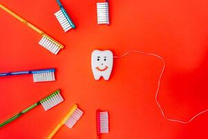 arreglando dental esenciales en un vibrante círculo. cepillos de dientes y pasta dental arreglado en un circulo en un rojo antecedentes foto