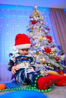 A Joyful Little Boy Admiring the Festive Christmas Tree. A little boy sitting in front of a christmas tree photo