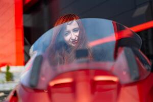 un mujer mirando fuera el ventana de un rojo coche. un mujer mirando fuera el ventana de un rojo coche foto
