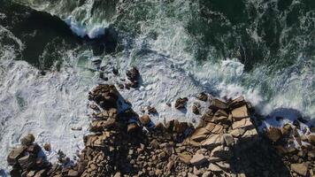 Top-down view of powerful storm waves rolling onto the rocky shore video