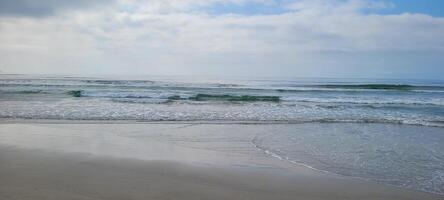 imagen de playa con blanco arena y calma mar en soleado día con bañistas y surfistas en el playa foto