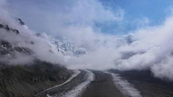 Mountains fog snow-covered peaks wild terrain aerial view. Mountains fog embodying wild nature's beauty Clouds blanket rugged mountains fog Capturing essence of untouched majestic nature. video