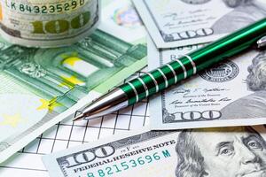 A Pile of Money with a Pen Resting on Top. A pen sitting on top of a pile of money photo