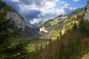 a mountain range with trees and a river photo