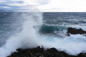 a wave crashing into the rocks photo