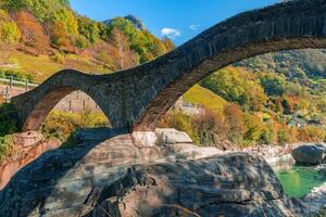 a stone bridge over a river in the mountains photo