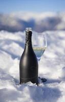 a bottle of wine and a glass sitting on top of snow photo