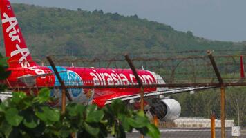 Phuket, Tailandia - febbraio 22, 2023. civile aereo airbus a320, hs-bbi di tailandese airasia partenza a Phuket aeroporto. Visualizza attraverso il aeroporto recinzione, aereo eccesso di velocità su per decollare video