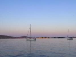 two sailboats floating in the water at dusk photo