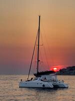 a catamaran sailing in the ocean at sunset photo