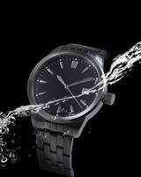 un negro reloj con agua salpicaduras en eso foto