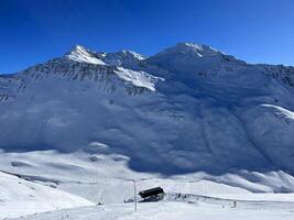 a person skiing down a snowy mountain with a blue sky photo