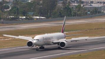 phuket, Tailandia - febrero 13, 2023. boeing 777 emiratos frenado después aterrizaje a phuket aeropuerto. chorro avión pasajero vuelo llegando spoilers arriba. turismo y viaje concepto video