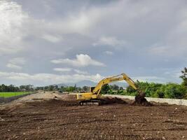 Oeste lombok regencia, Indonesia - febrero 4, 2024. al aire libre, un retroexcavadora es a trabajo arrasamiento el suelo para un alojamiento sitio, con un azul cielo en el antecedentes. foto