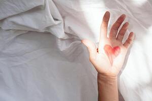 Palm of hand in bed at the morning. Valentines day concept. photo