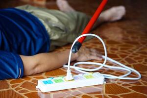 utilizando rojo el plastico palo es Moviente lejos el eléctrico enchufe enchufe desde el inconsciente hombre quien laico abajo en el piso. concepto, eléctrico choque. emergencia básico rescate. primero ayuda foto