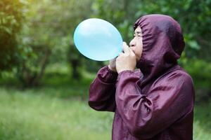 Asian man is blowing, inflating air into a balloon in the park. Concept, prepare balloon for playing games as a toy, decorate party or celebration. Recreation or leisure activity. Fun and happy time. photo