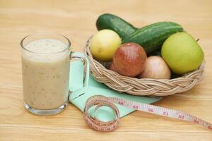 Glass of smoothie mixed fruits, basket of fresh fruits and measuring tape. Concept, healthy beverage for health. Well being and weight loss menu. Homemade refreshing fruit drinks. High fibers, detox. photo