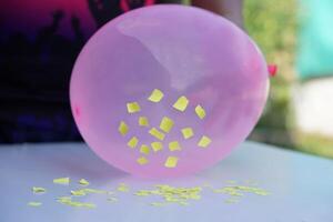 Closeup hand hold pink balloon to do science experiment about static electricity from balloon and pieces of paper. Concept, Science lesson, fun and easy experiment. Education. Teaching aids. photo